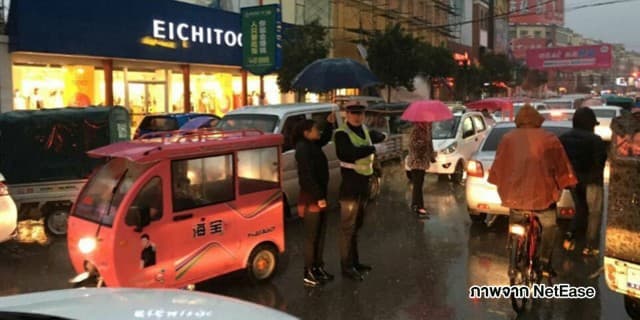 หญิงจีนยืนกางร่มให้ ตร.จราจร นานกว่าครึ่งชม. ท่ามกลางฝนที่ตกลงมาอย่างหนัก